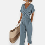 Femme portant une combinaison pantalon beige avec cache-cœur drapé et jambes larges